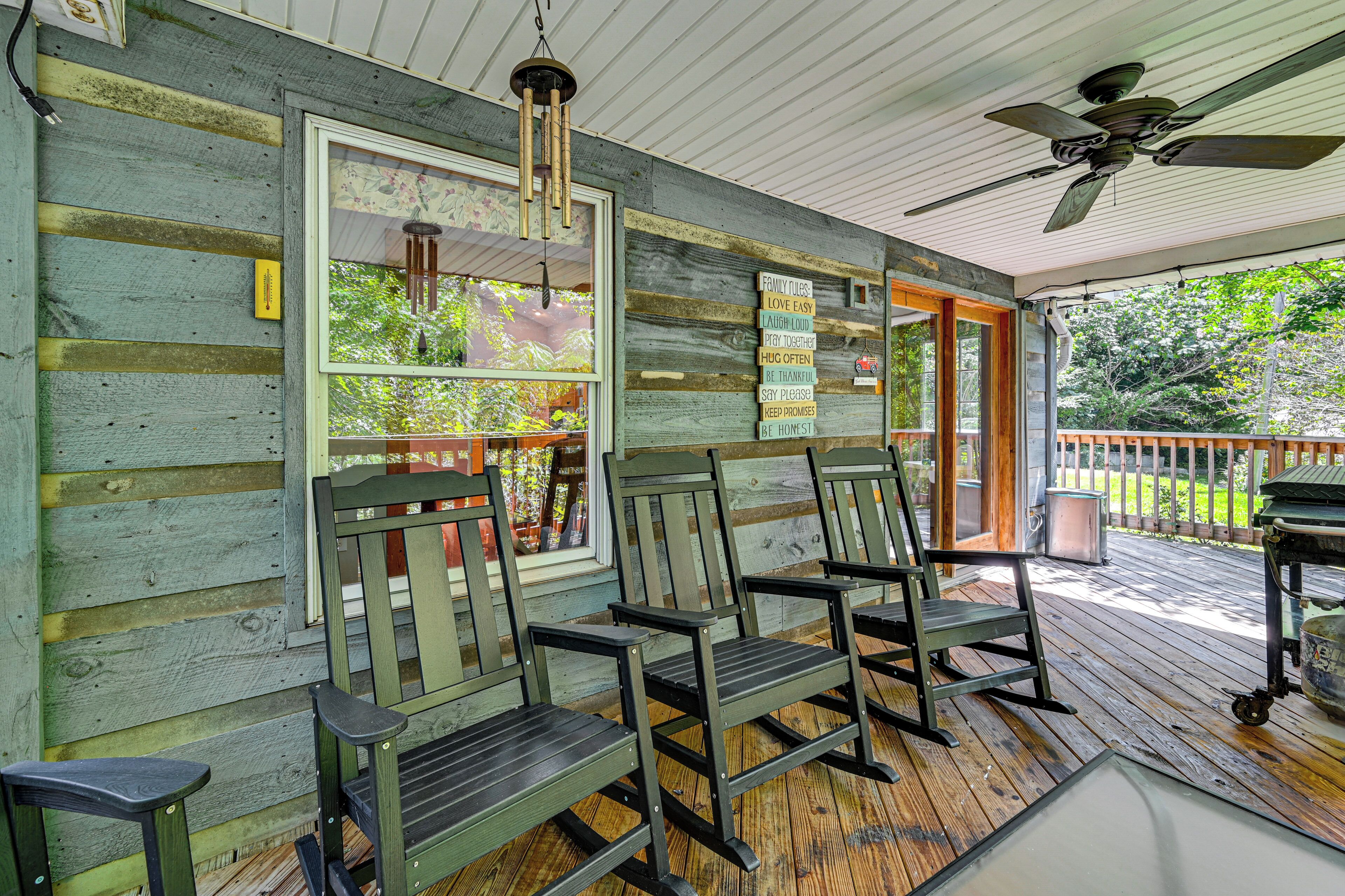 A porch with wooden chairs, a ceiling fan, and a view of the outdoors.