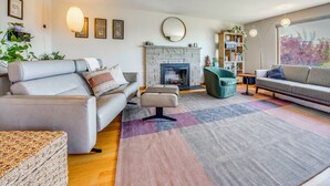A modern living room with a fireplace, sofas, and a bookshelf. - 1/2 Mi to Alki Beach + Puget Sound Views! (Seattle)