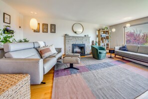 A modern living room with a fireplace, sofas, and a bookshelf. - 1/2 Mi to Alki Beach + Puget Sound Views! (Seattle)