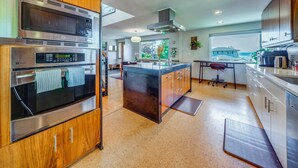 A modern kitchen with stainless steel appliances, wooden cabinets, and a large island. - 1/2 Mi to Alki Beach + Puget Sound Views! (Seattle)