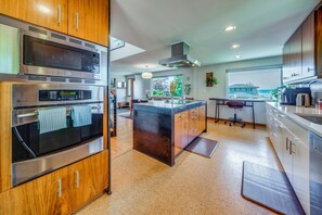 A modern kitchen with stainless steel appliances, wooden cabinets, and a large island. - 1/2 Mi to Alki Beach + Puget Sound Views! (Seattle)