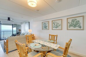 A dining area with a round glass table, surrounded by wooden chairs with cushioned seats. - Gulf-front SPI Condo: Suntide III - Unit 1009 (South Padre Island)