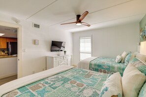 A bedroom with two beds, a ceiling fan, a television, and a window with blinds. - Gulf-front SPI Condo: Suntide III - Unit 1009 (South Padre Island)