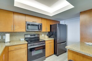 A modern kitchen with a skylight, stainless steel appliances, and wooden cabinetry. - Gulf-front SPI Condo: Suntide III - Unit 1009 (South Padre Island)