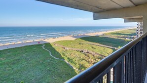Ein Balkon mit Blick auf einen Strand, mit freiem Blick aufs Meer und einer Rasenfläche.