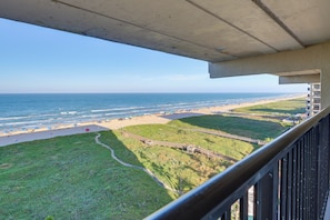 Ein Balkon mit Blick auf einen Strand, mit freiem Blick aufs Meer und einer Rasenfläche.