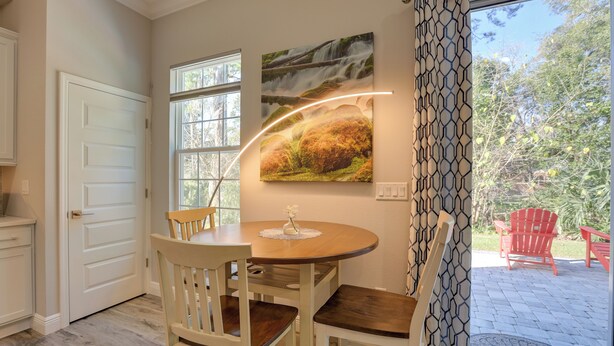A dining area with a round table, chairs, and a wall-mounted picture. - Twin Ocala Townhomes! 1 Mi to WEC (Ocala)