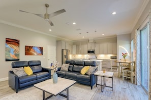 A modern living room with a black leather sofa, a coffee table, and a ceiling fan. - Gateway to Wec! Twin Ocala Townhomes (Ocala)