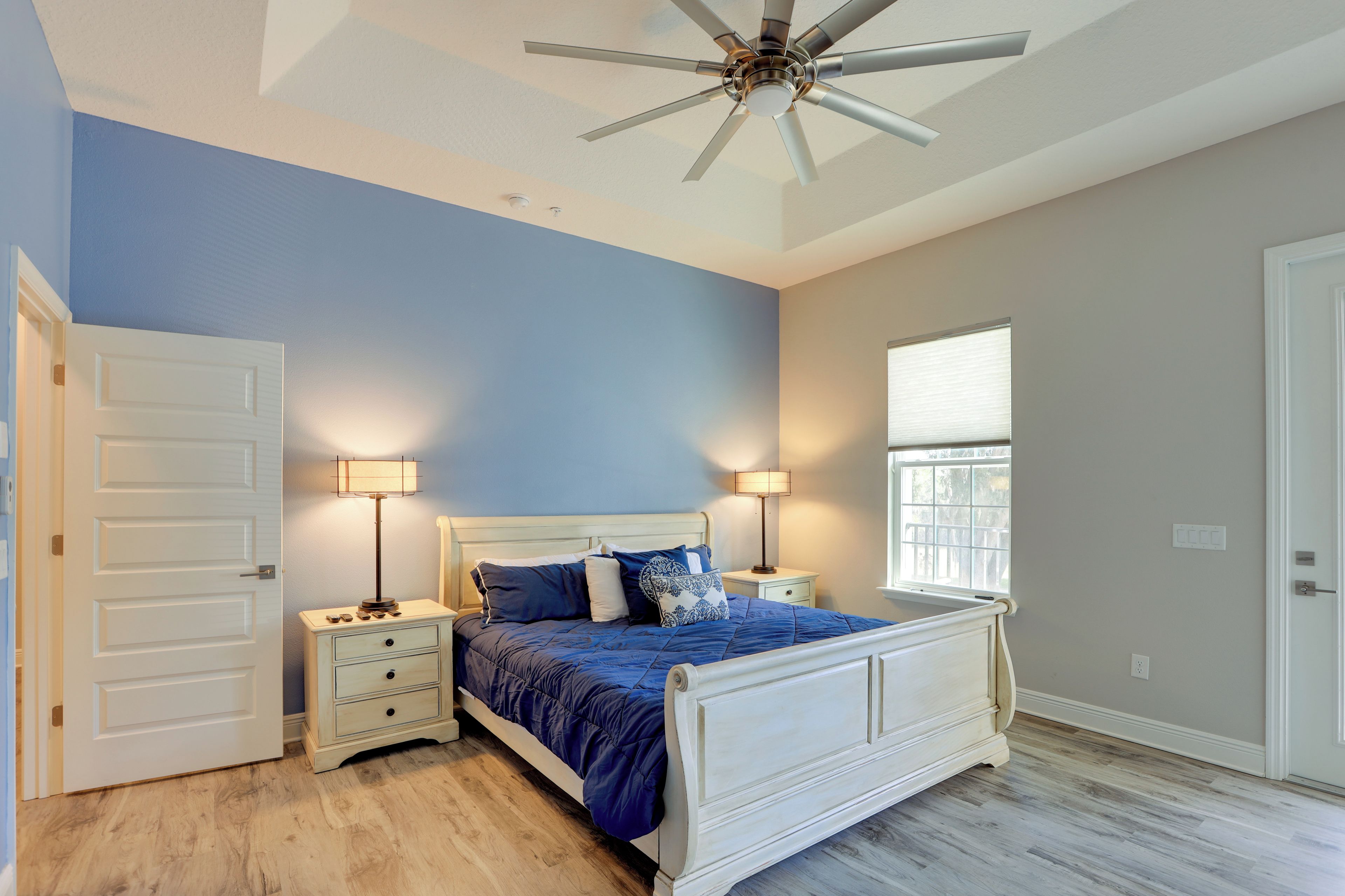 A bedroom with a bed, nightstands, a ceiling fan, and a window.