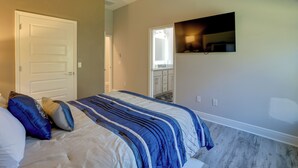 A bedroom with a bed, a door, a television mounted on the wall, and a window. - Twin Ocala Townhomes! 1 Mi to WEC (Ocala)