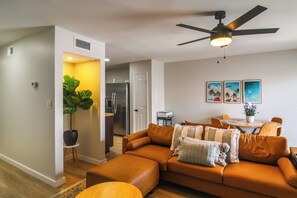 A modern living room with a leather sofa, a ceiling fan, and a dining area with a table and chairs. - Walk to Beach! Prime Okaloosa Island Townhome (Fort Walton Beach)