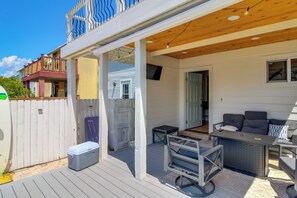 A covered outdoor patio with a seating area, a small table, and a cooler. - Walk to Beach! Prime Okaloosa Island Townhome (Fort Walton Beach)