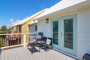 Ein Balkon mit Gartenmöbeln, eine Tür mit Fenster und ein Geländer.