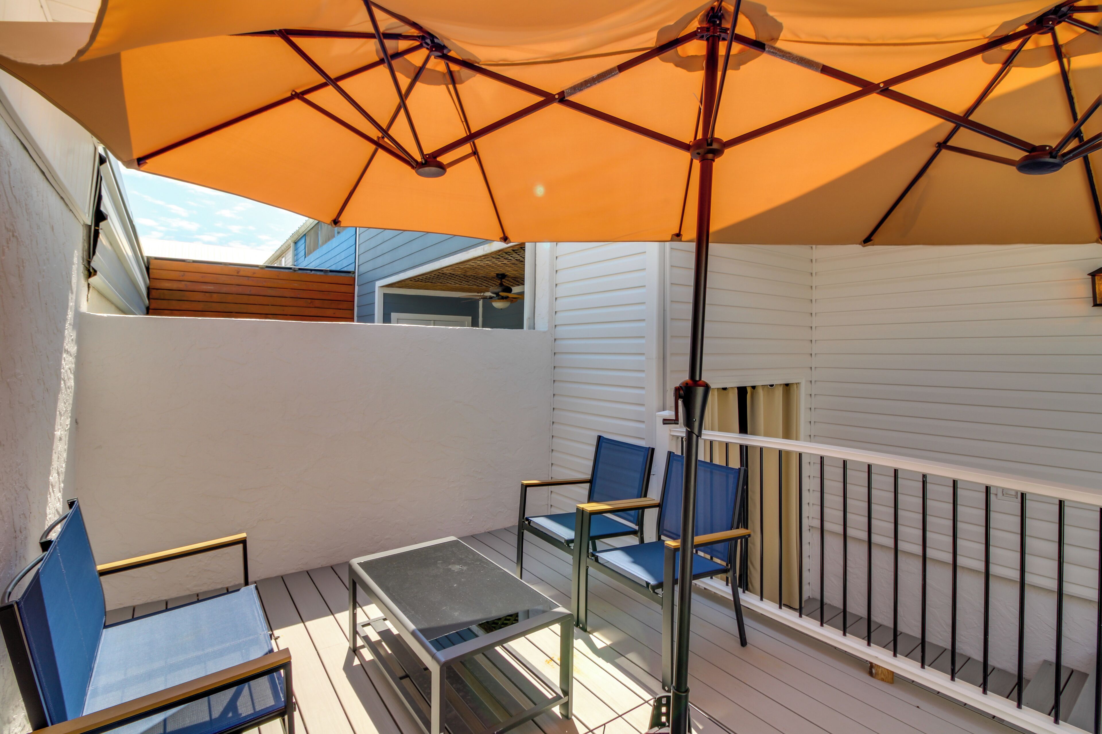A balcony with a table and chairs, an umbrella, and a railing.