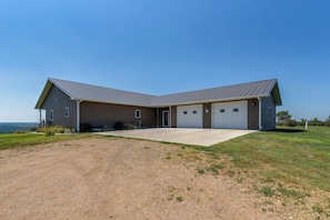 A two-story house with a garage, a driveway, and a grassy lawn.