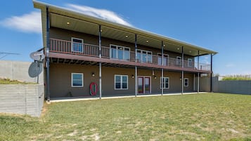 A two-story building with a covered balcony, a satellite dish, and a well-maintained lawn.