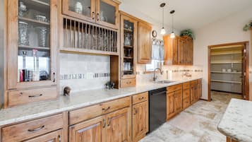 Una cocina con armarios de madera, lavavajillas y encimera de mármol.