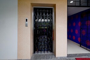 A door with a metal gate, a wall with a patterned design, and a tiled floor. - Hotel O Netaji Park Hyderabad (Hyderabad)