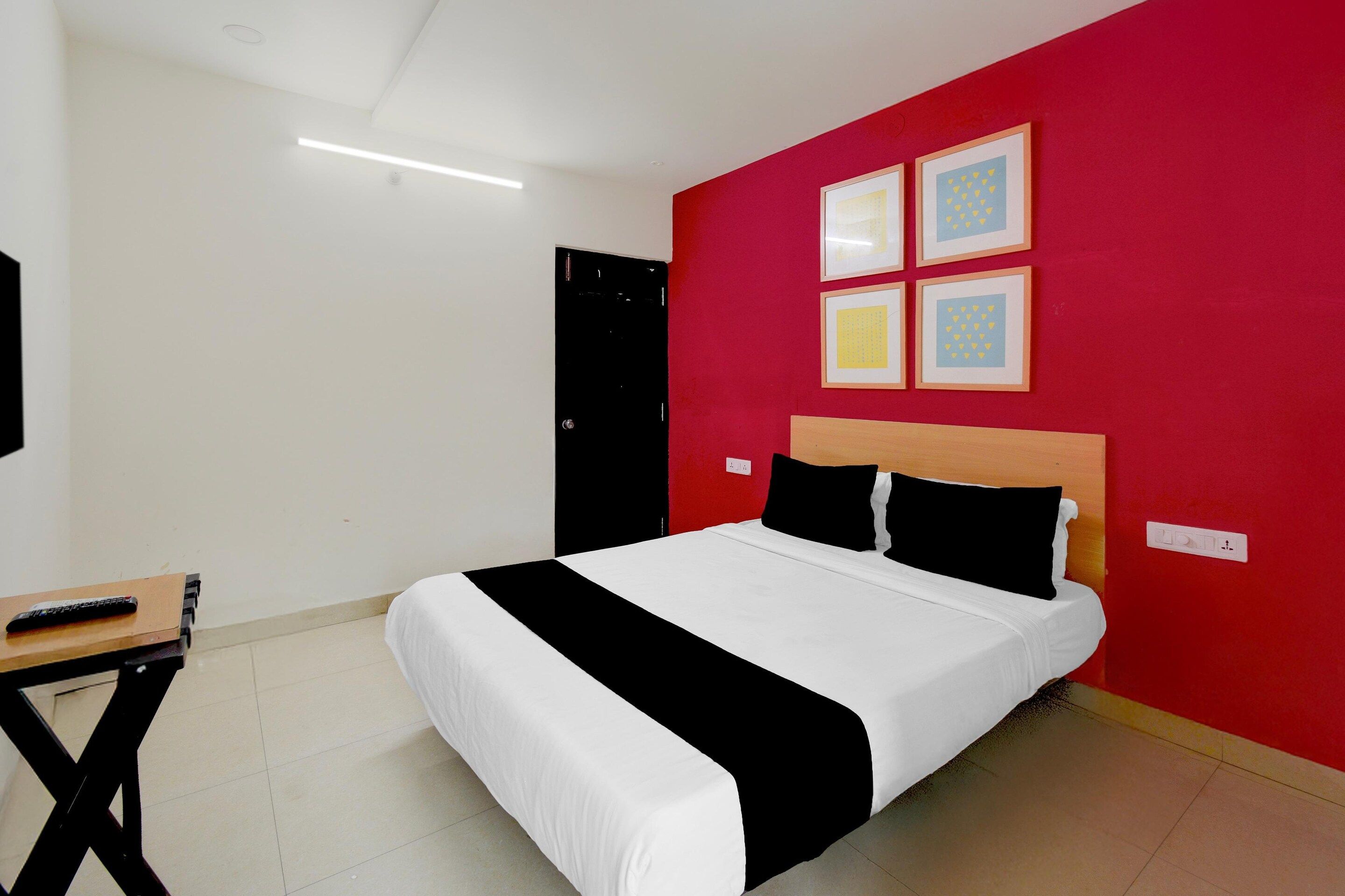 Une chambre d’hôtel avec un lit, un bureau et un mur d’accent de couleur rouge.