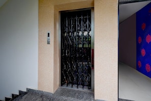 A staircase leading to a door with a metal gate. - Hotel O Netaji Park Hyderabad (Hyderabad)