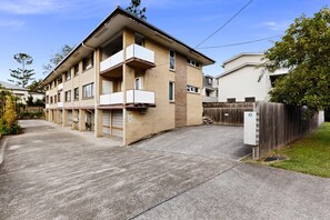 Ein mehrgeschossiges Wohngebäude mit Backsteinfassade, einem verschlossenen Einfahrtsweg und einem eingezäunten Garten.