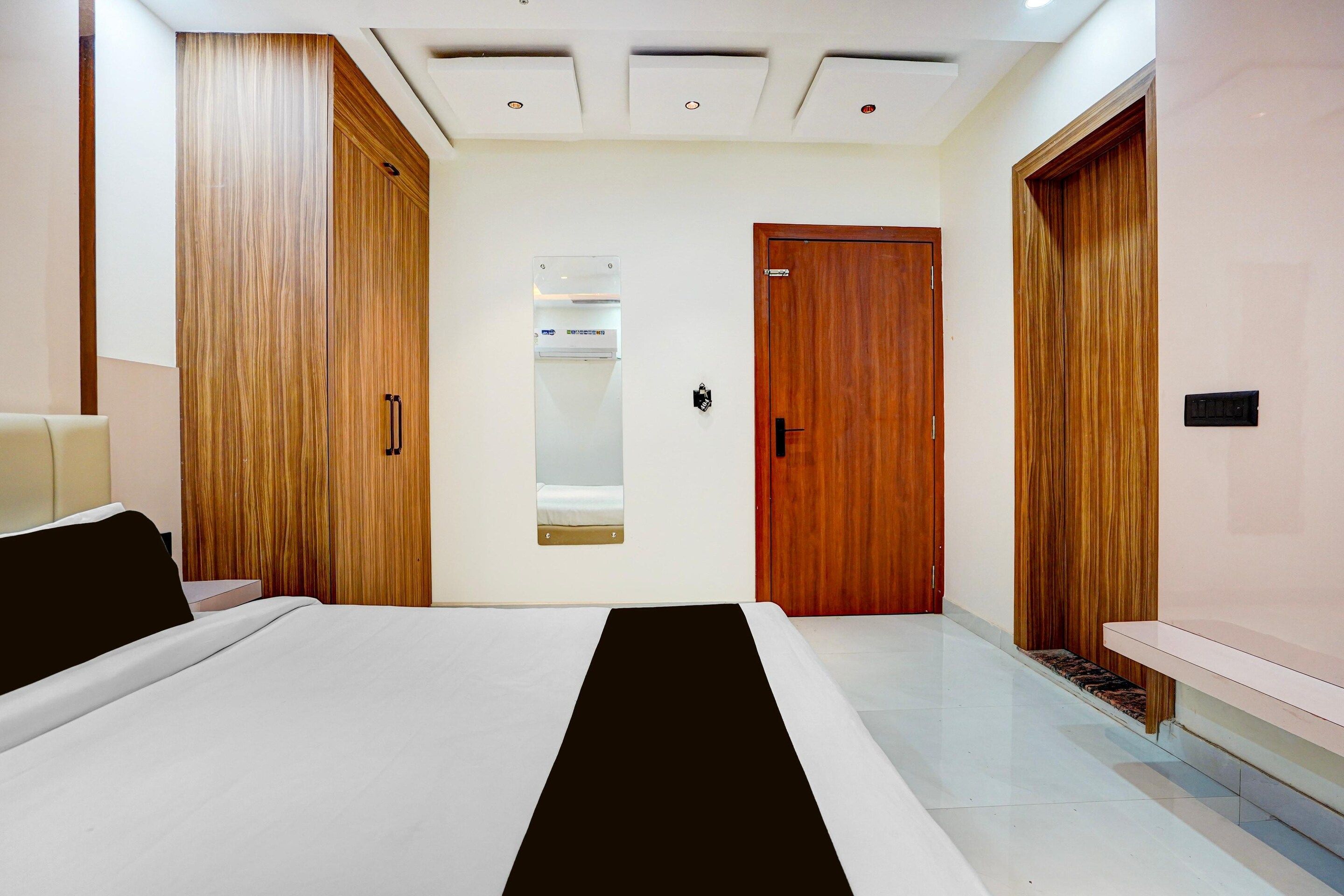 A modern bedroom with a bed, wooden wardrobe, a mirror, and a door.