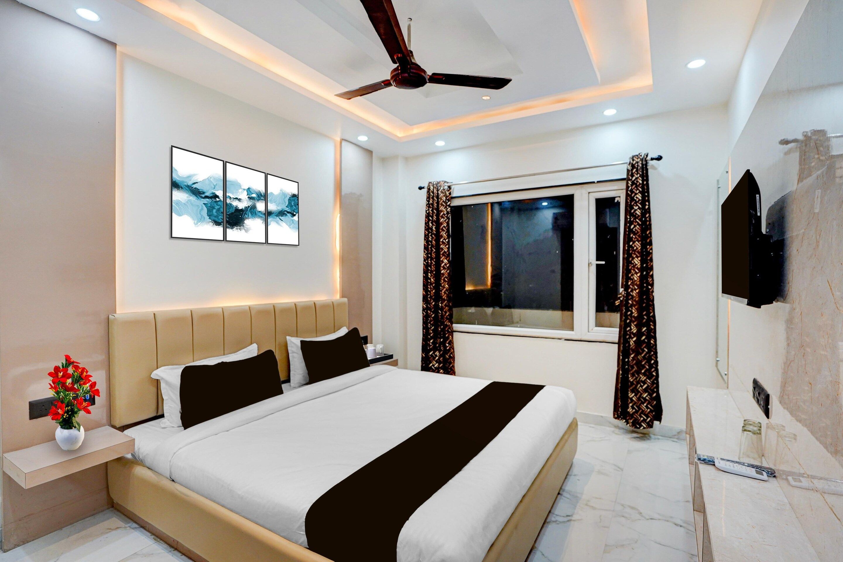 Una habitación de hotel moderna con cama, mesita de noche, obra de arte y ventilador de techo.