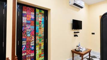 Una habitación de hotel con piso a cuadros, un televisor, un equipo de aire acondicionado y una puerta colorida.