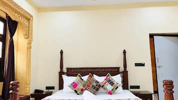A hotel room with a wooden bed, a ceiling fan, and a decorative wall panel.
