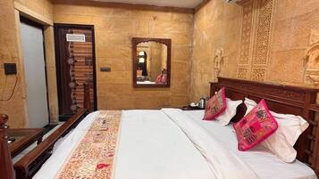 Quarto de hotel com uma cama grande, um ventilador de teto, um aparelho de ar condicionado e um tapete estampado.
