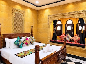 Una habitación tradicional con cama, almohadas y ventana con cortinas.