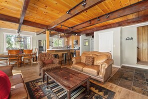 A spacious living room with a leather sofa, a wooden coffee table, and a patterned rug. - Sophie's Den- BLS Rec access, sleeps 12 (Arnold)