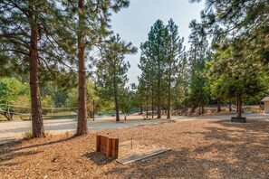 A park with tall pine trees, a wooden bench, and a dirt path. - Sophie's Den- BLS Rec access, sleeps 12 (Arnold)
