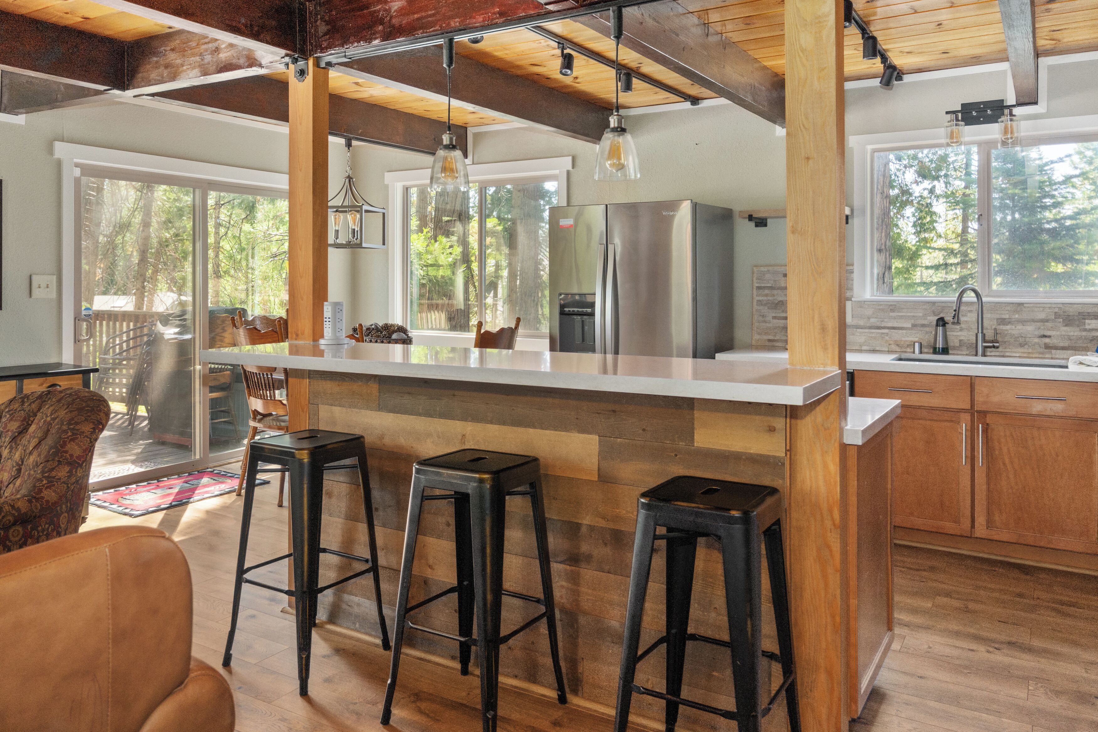 Una cocina moderna con una isla central, taburetes de bar y vistas al exterior.