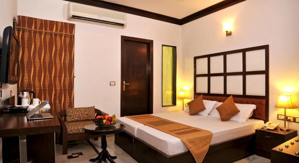 Une chambre d’hôtel comprenant un lit, une table de chevet, une chaise, un bureau et une petite table avec des fruits.
