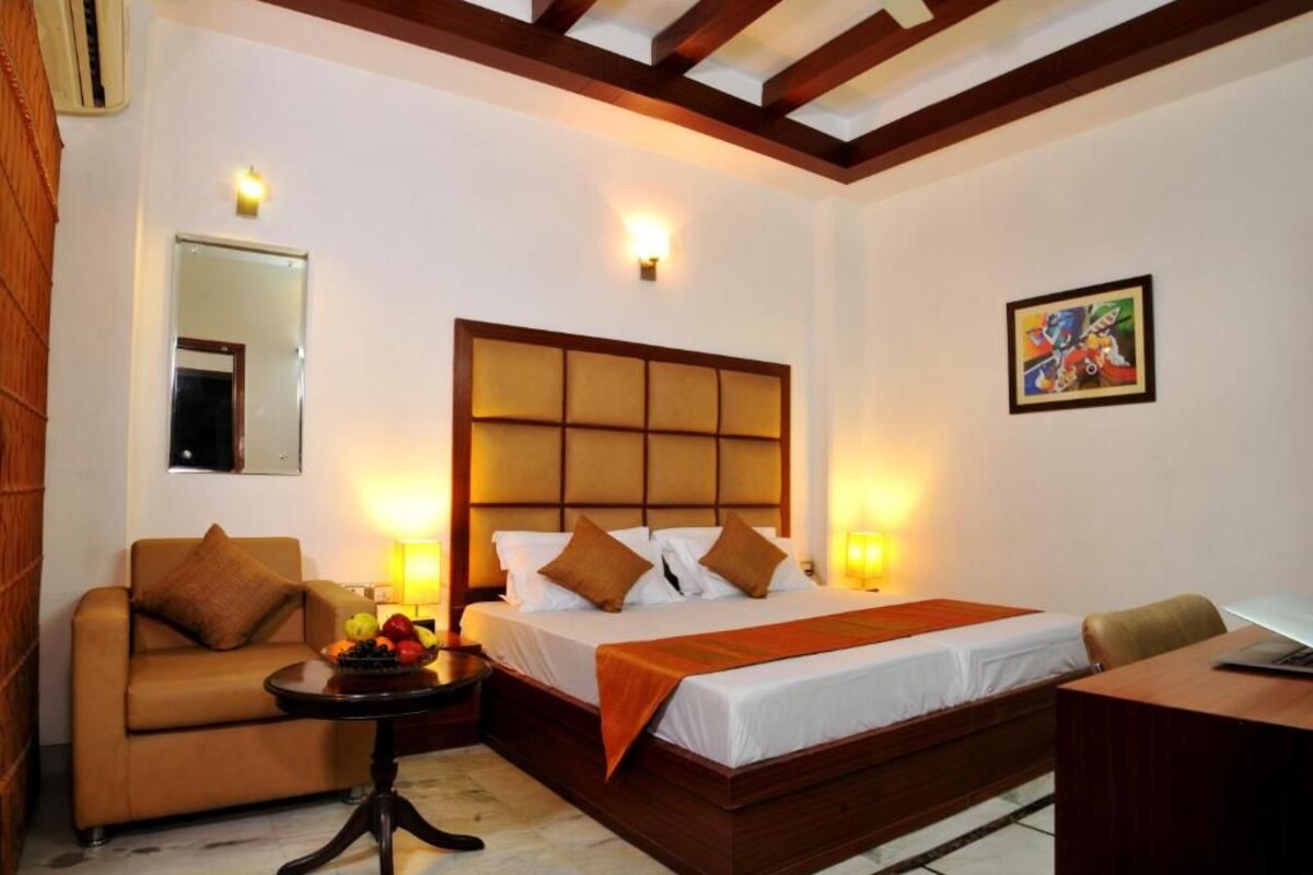 A hotel room with a bed, a sofa, a small table with fruit, and a desk.
