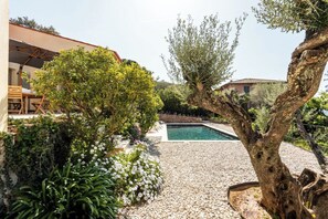 A pool surrounded by a gravel area with trees and a wooden deck. - Luxury Charm Villa Heart of village, large swimming pool, large private garden (Grimaud)