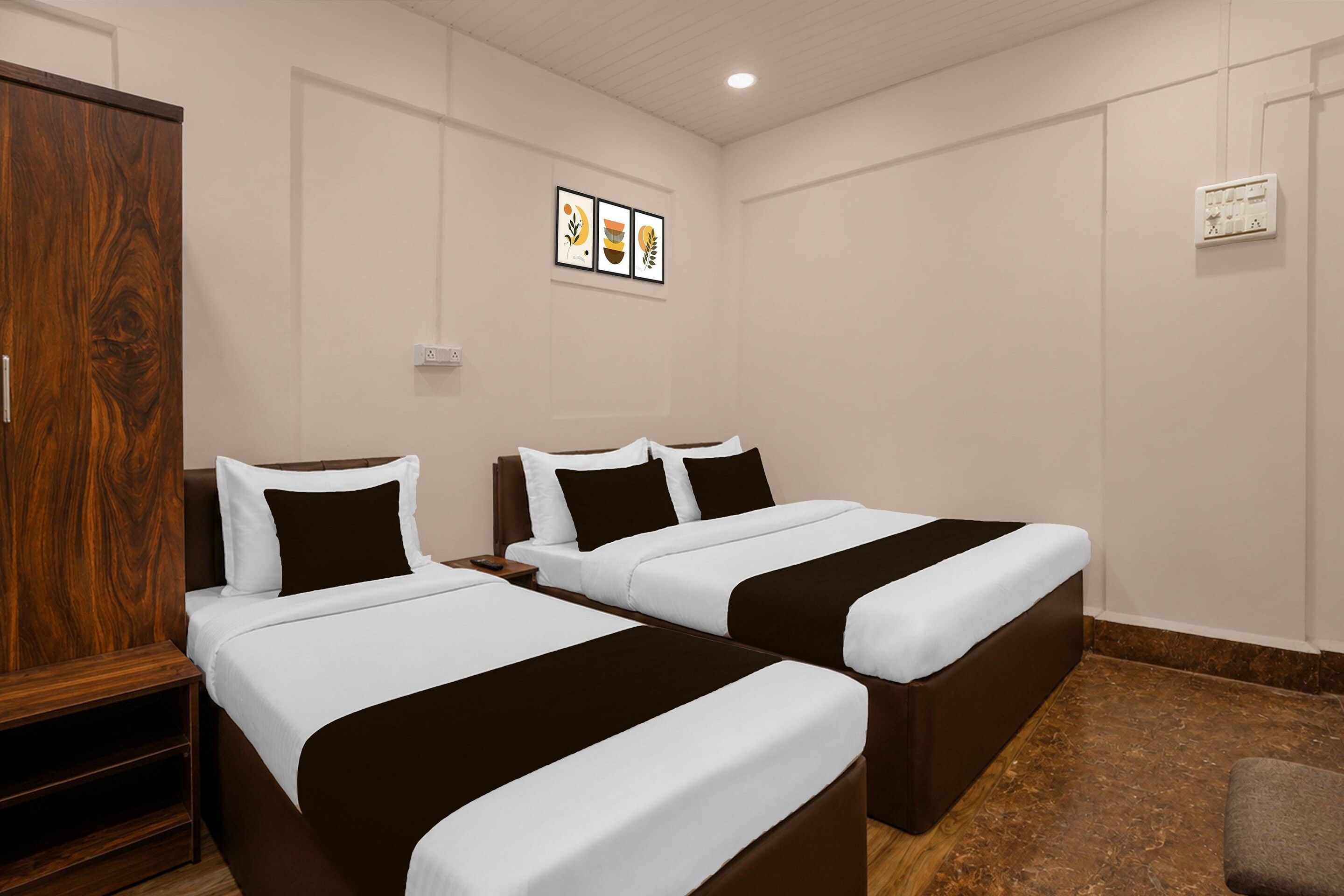 A hotel room with two beds, a wardrobe, and a wall-mounted power outlet.