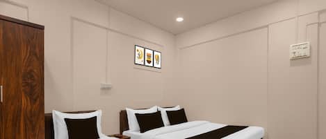 Habitación de hotel con dos camas, un armario y un enchufe en la pared.