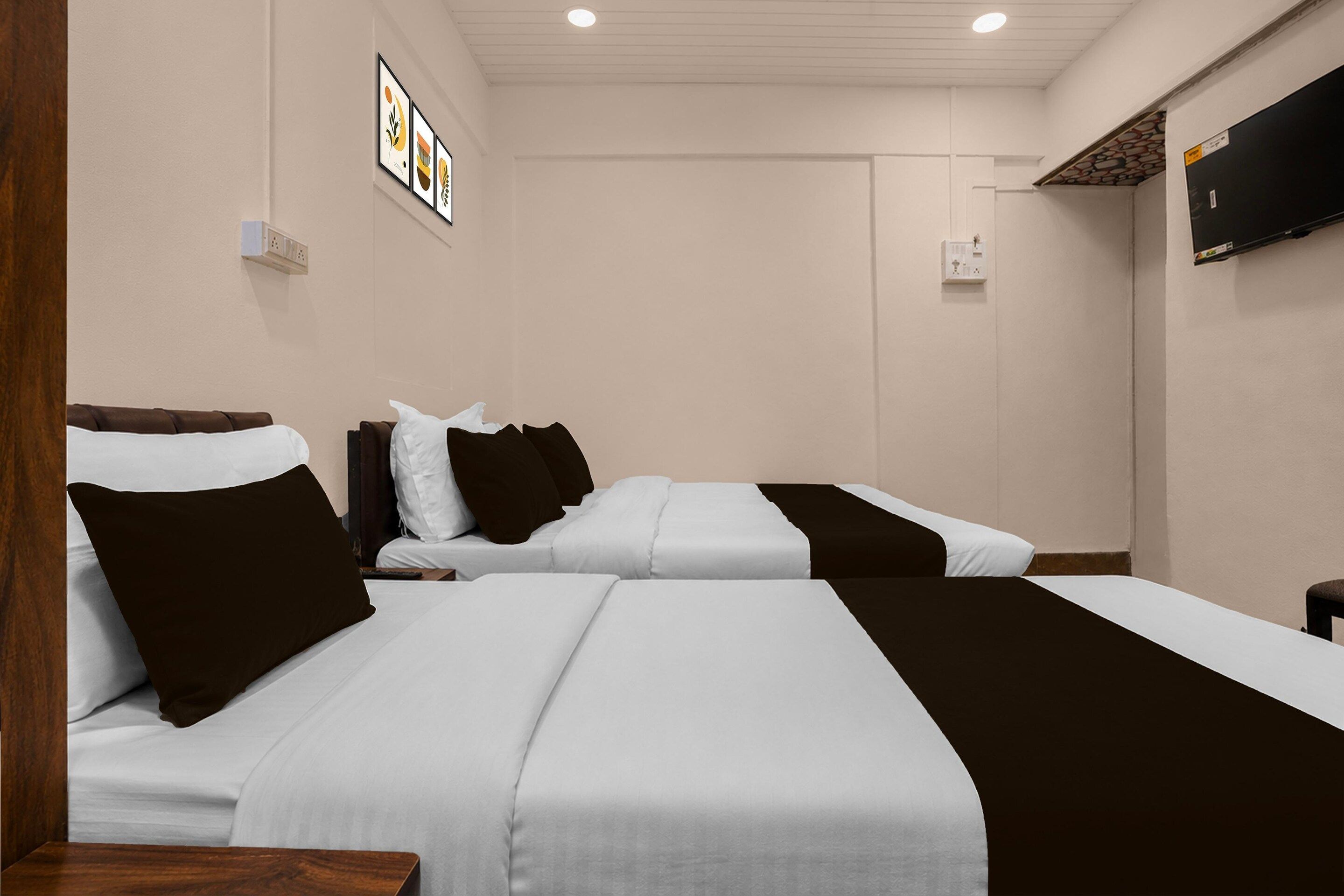 A hotel room with two beds, a flat-screen TV mounted on the wall, and a small table.