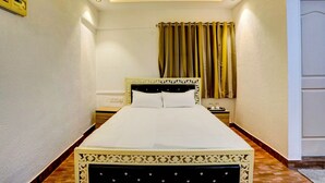 A hotel room with a bed, bedside table, nightstand, and a ceiling fan. - Deluxe Room Santacruz Metro (Mumbai)