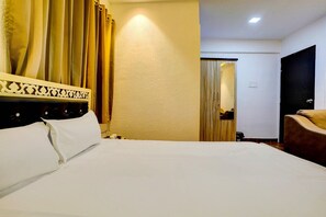 Ein Hotelzimmer mit einem Bett, einem Sessel, einer Holztür und einem Spiegel.