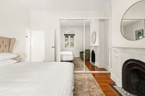 A bedroom with a bed, a mirror, a fireplace, and a door leading to another room. - Stylish 3BR Terrace Near Sydney CBD & Usyd (Sydney)