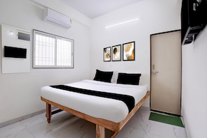A bedroom with a bed, a window, an air conditioning unit, and three framed artworks on the wall. - Hotel O Bamu University (Chhatrapati Sambhajinagar)
