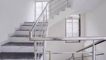 A staircase with a metal handrail and glass doors leading to another level.