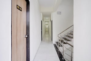 A hotel corridor with a wooden door marked '101', a marble floor, and a staircase with metal railings.