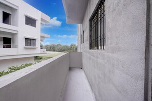 A narrow outdoor corridor with a white building on one side and a clear blue sky.