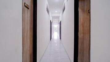 Un pasillo largo y estrecho con puertas de madera a ambos lados, que conduce a una habitación luminosa al final.