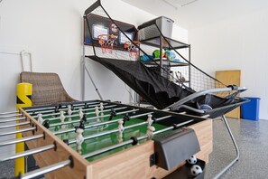 A foosball table with a netted basketball hoop in the background. - Peaceful 3-bedroom house with AC in charming Largo (Largo)