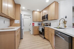A modern kitchen with wooden cabinets, stainless steel appliances, and a white countertop. - Peaceful 3-bedroom house with AC in charming Largo (Largo)